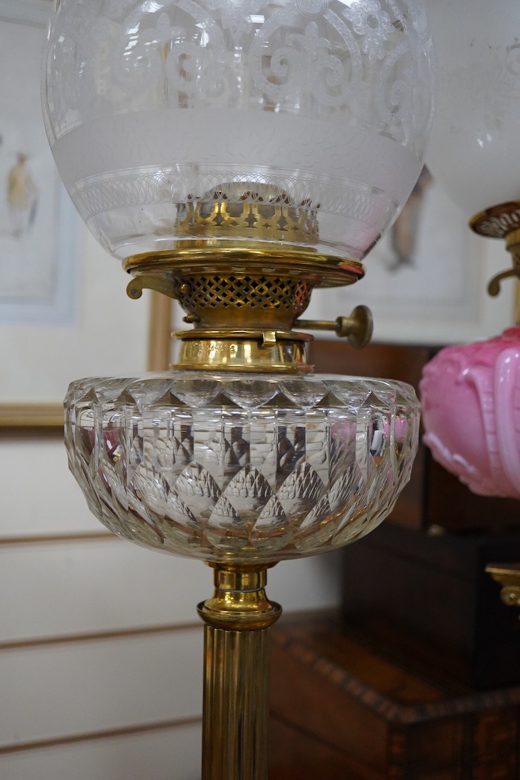 Three Victorian brass column oil lamps, with original brass fittings, glass reservoirs and shades. Tallest 72cm high.